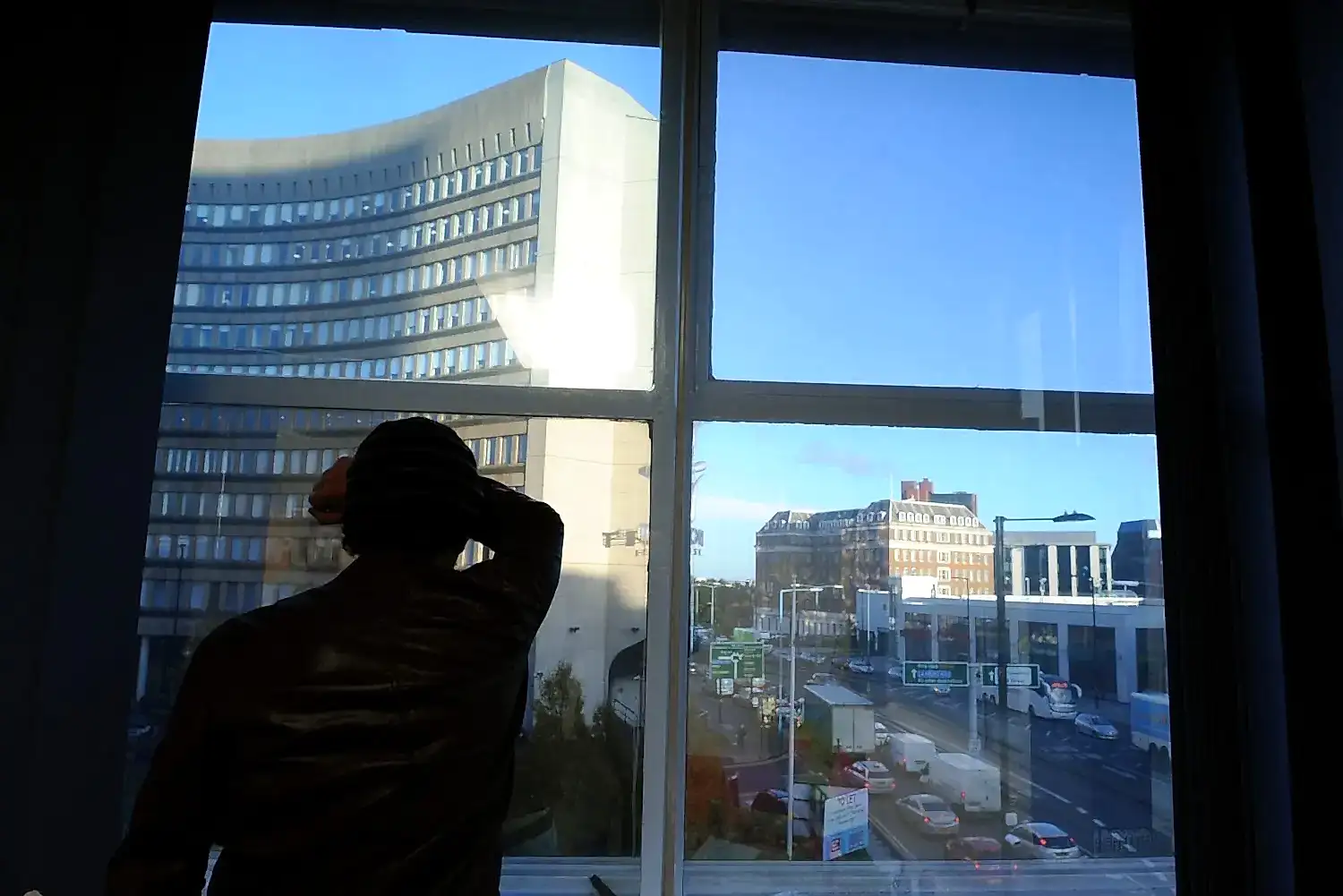 Picture of a young man looking out of a window at a city view