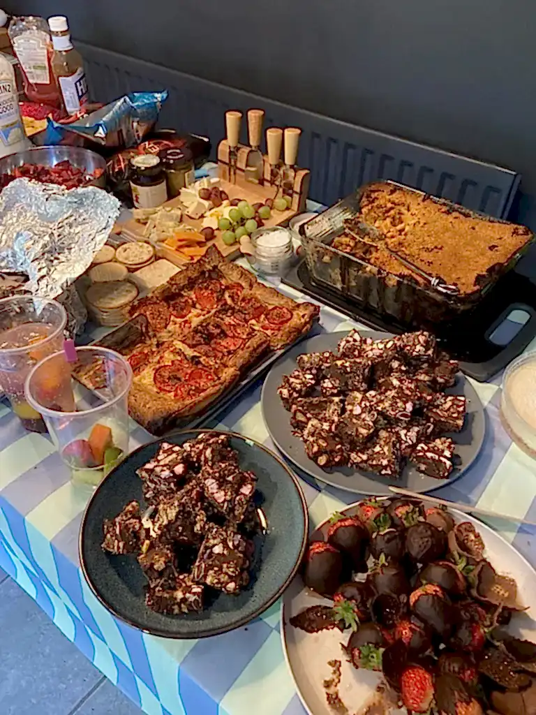 A table of delicious food including chocolate stawberries and a tomato tart.